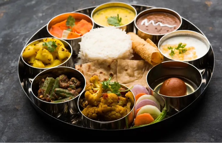 Home-style vegetarian thali with daal, rice, roti and seasonal sabzi in steel bowls